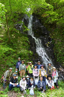 和滝の前で集合写真に納まる参加者たち