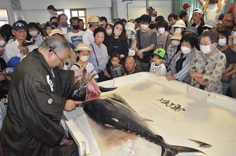 鼠ケ関港で水揚げされたマグロの解体ショーが行われ、家族連れが興味深そうに切り分ける様子を見守った