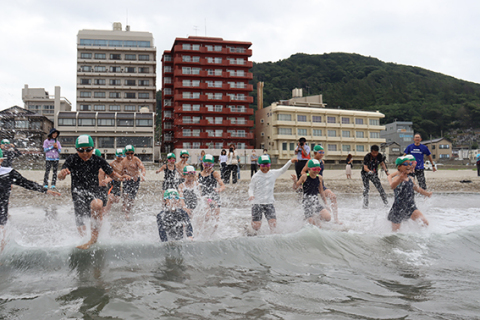 水しぶきを上げて海に入る湯野浜小の子どもたち＝湯野浜海水浴場