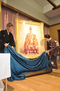 齋藤さん（左）と妻のみちさんが幕を引き、神社に掲げられる肖像画がお披露目された