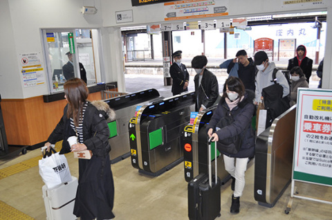 大きな荷物を手に、帰省客が次々と改札口を通り抜けた＝30日午前、ＪＲ鶴岡駅