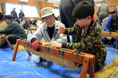 地域の高齢者に教わりながら俵を編む新堀小児童
