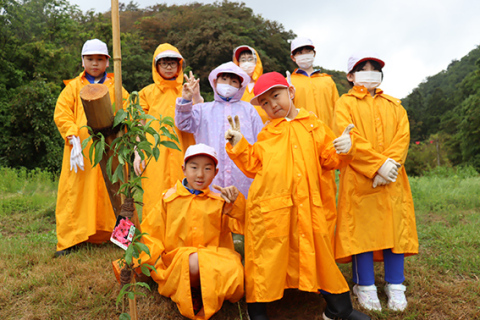 「大きく育ってほしいな」―。植樹を終えて記念撮影する子どもたち