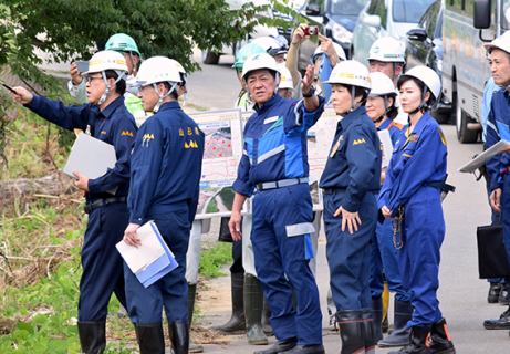 記録的大雨の被災地で被害が出た酒田市大沢地区を視察する松村大臣（中央）＝21日午後