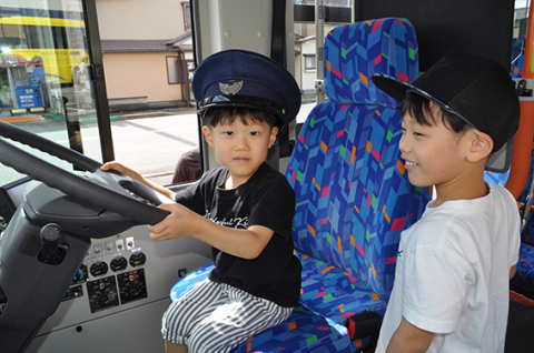 運転手の帽子をかぶって運転席へ試乗する子どもたち