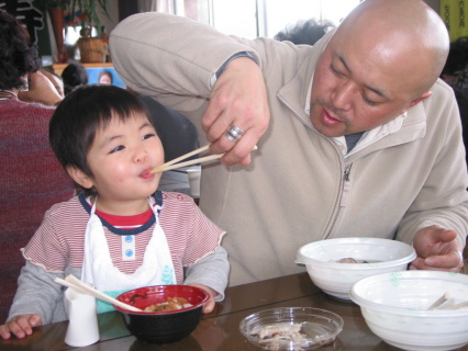 おいしい寒ダラ汁を父親に食べさせてもらい自然に笑顔が広がった＝鶴岡市由良の市フィッシングセンター