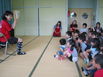 窪田隊長（左）の読み聞かせを聞く園児たち＝16日、朝日保育園