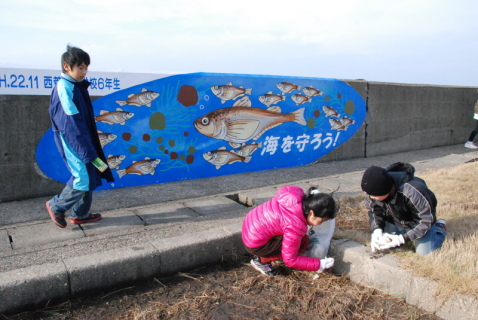 「ハタハタ壁画」の前で西荒瀬小の6年生たちが清掃活動