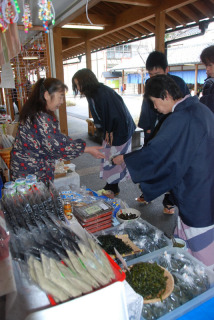 浴衣姿の温泉客が朝市を訪れ、目移りしながらお土産を選んでいた