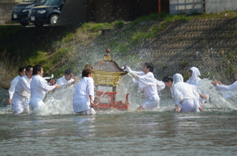 若者たちが川の中で威勢よく神輿に水を掛け、豊漁を願った＝鶴岡市鼠ケ関