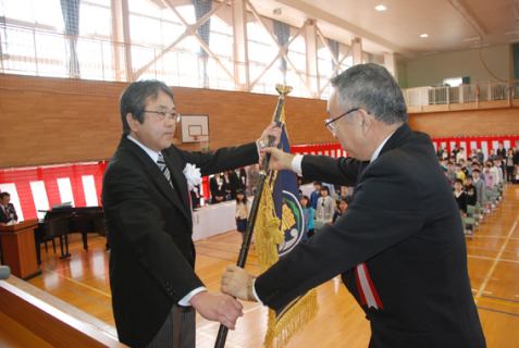 工藤校長（左）へ榎本市長から校旗が手渡された